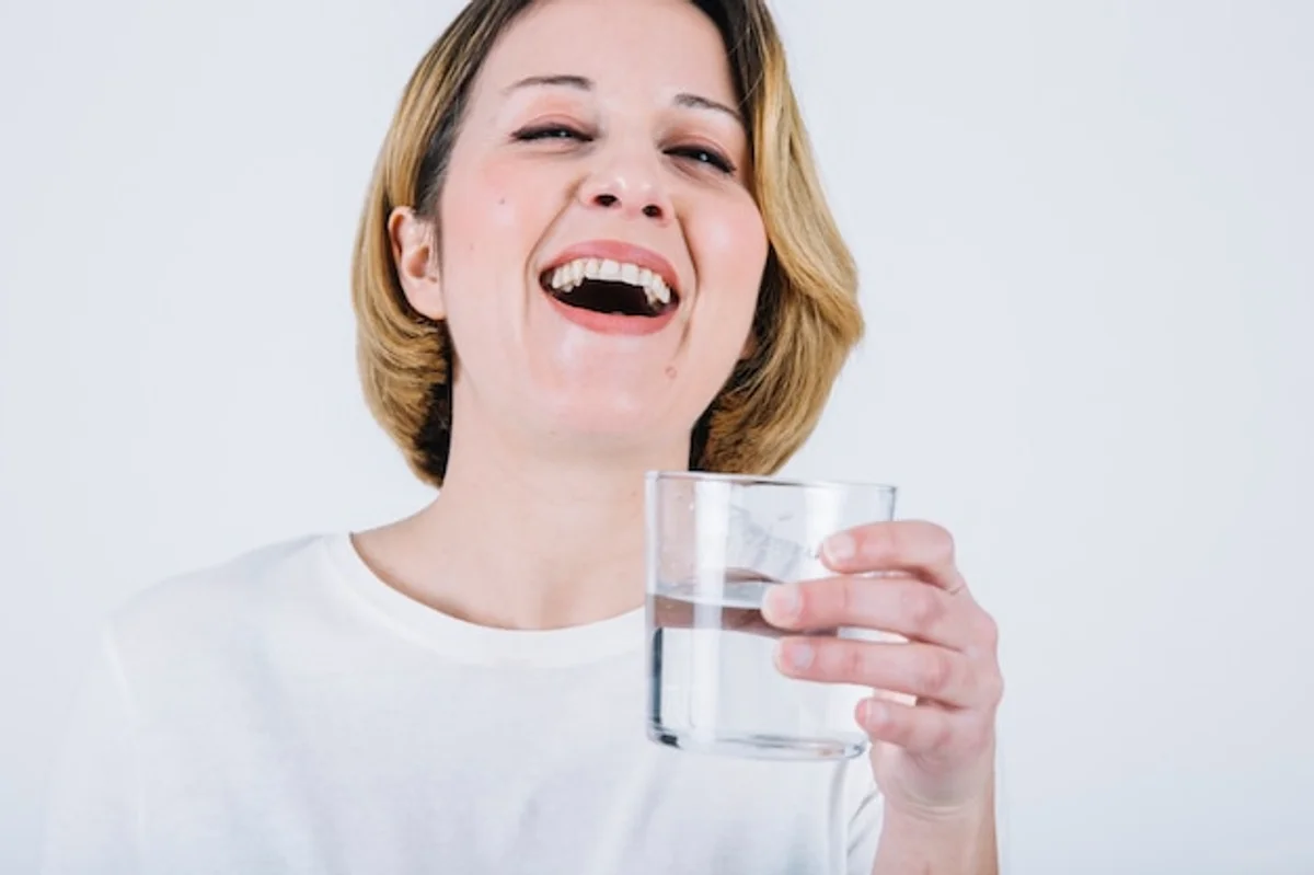 frau trinkt wasser glas lachend nahaufnahme