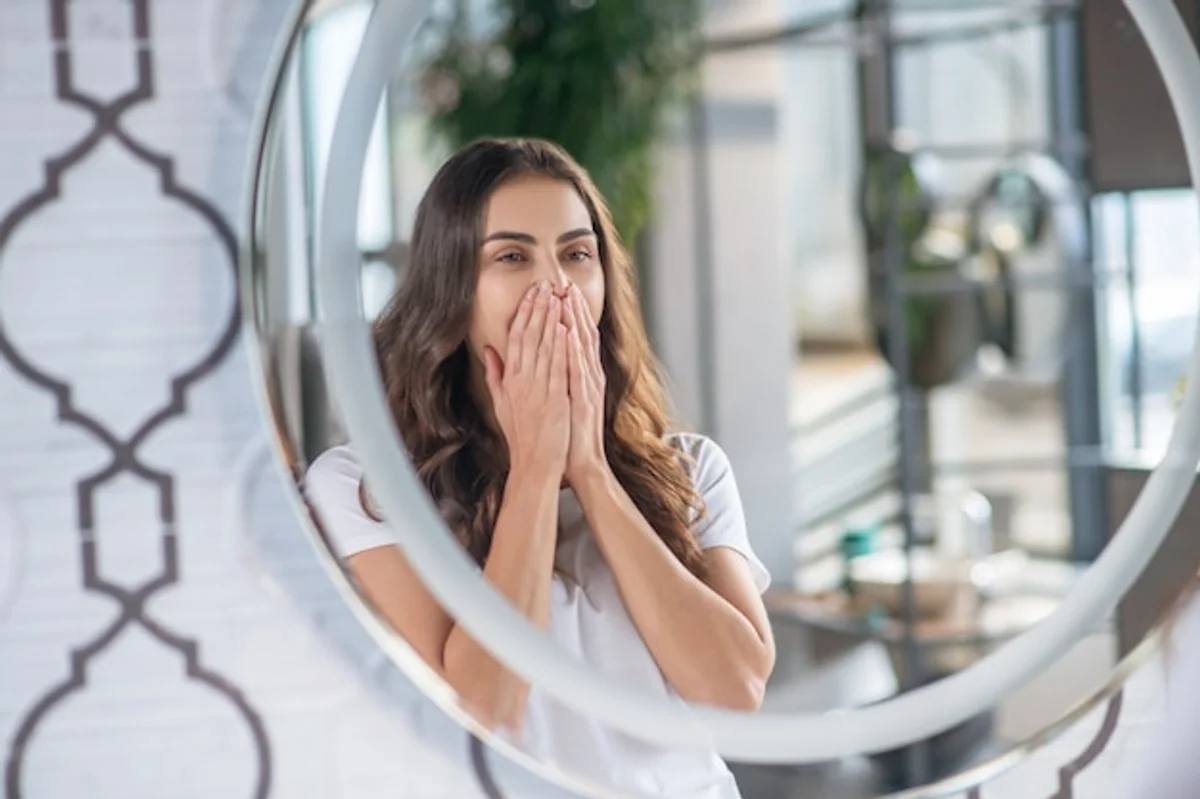 tired woman looking in bathroom mirror early morning