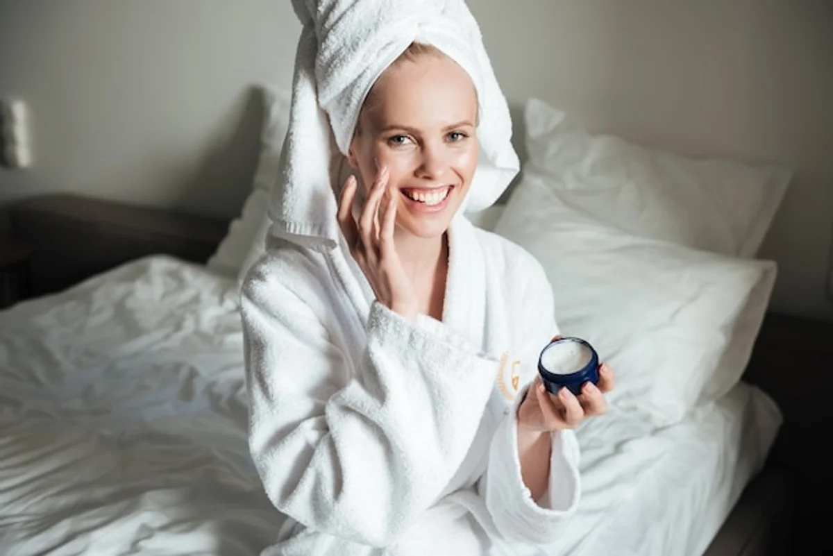 woman applying night cream looking relaxed in bedroom