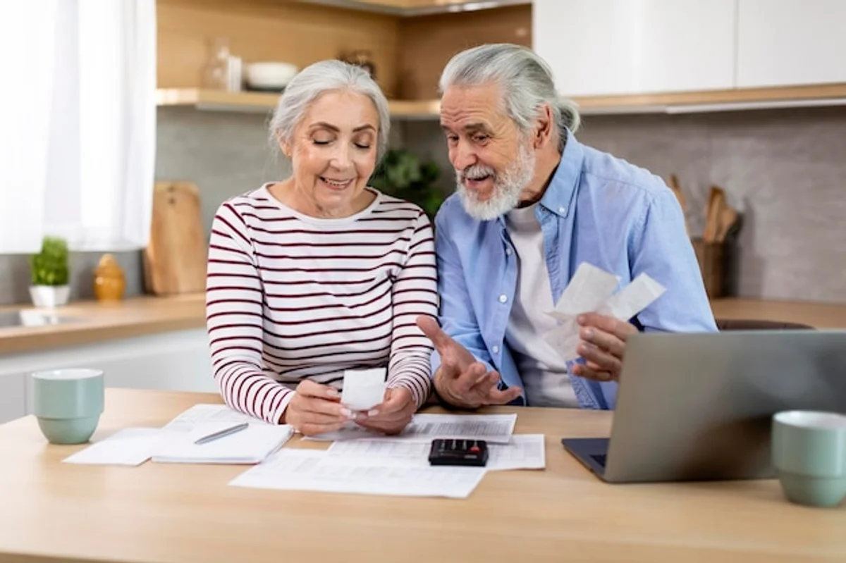 elderly couple smiling while budgeting finances at home