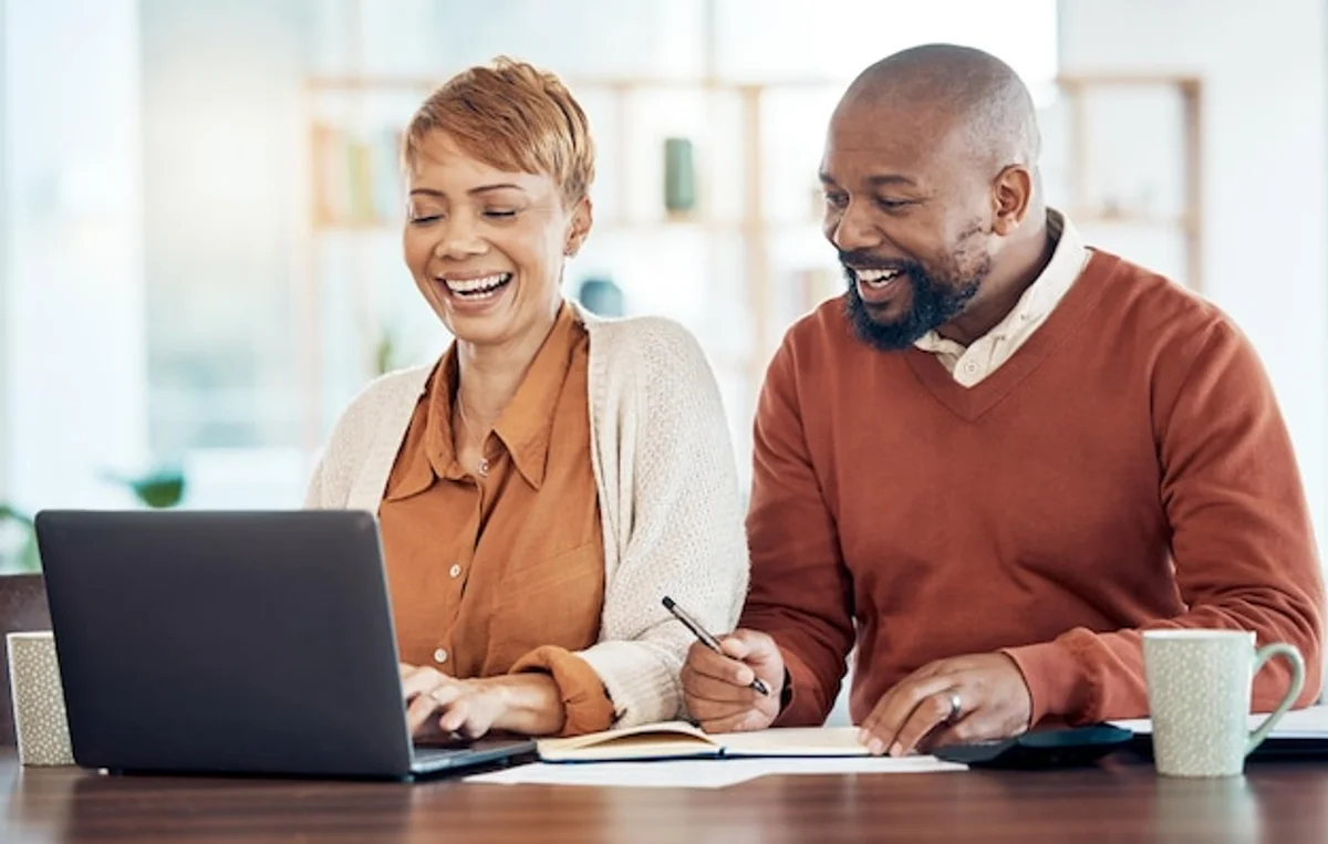 happy senior couple checking finances together smiling at home laptop