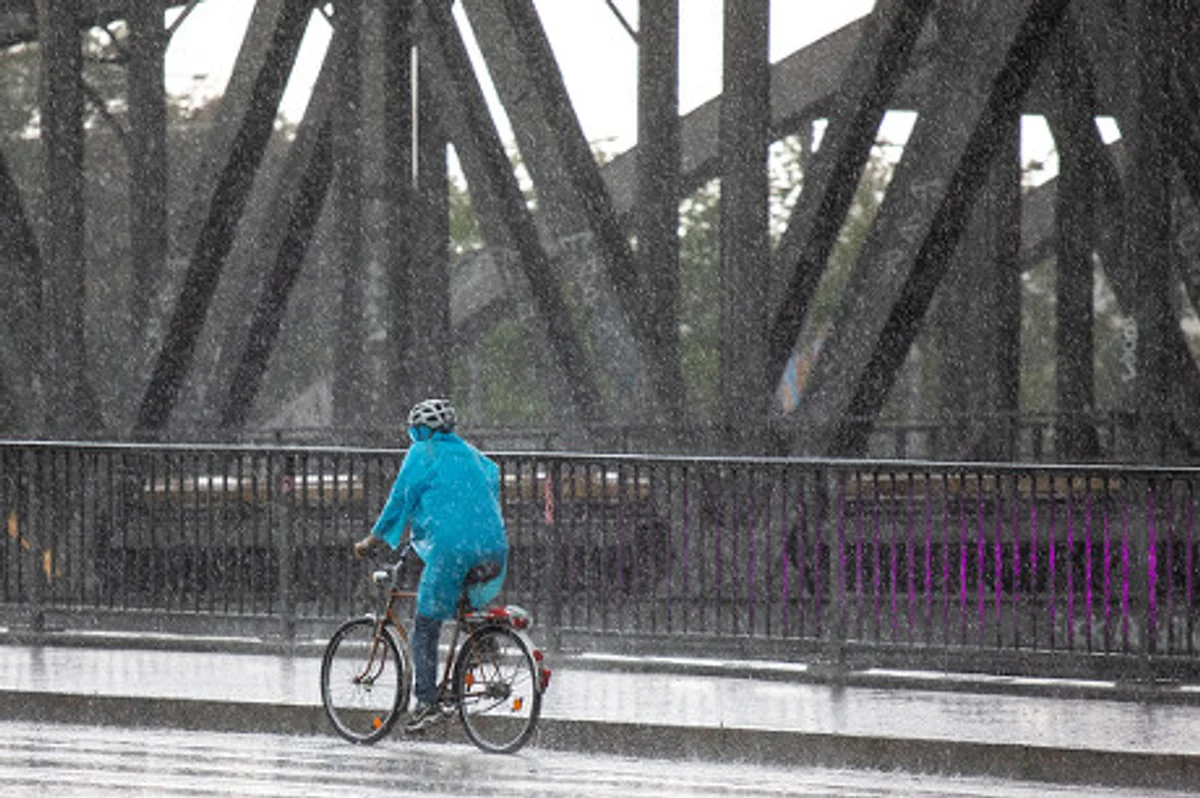 person with poncho riding bike rainy day germany