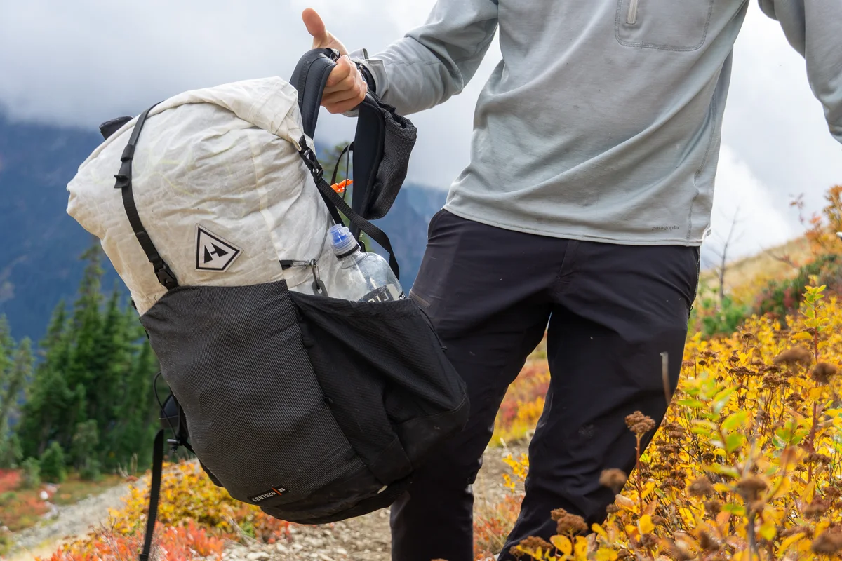 backpacker packing waterproof gear in alpine landscape