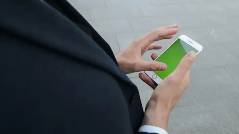man checking smartphone battery settings outdoors