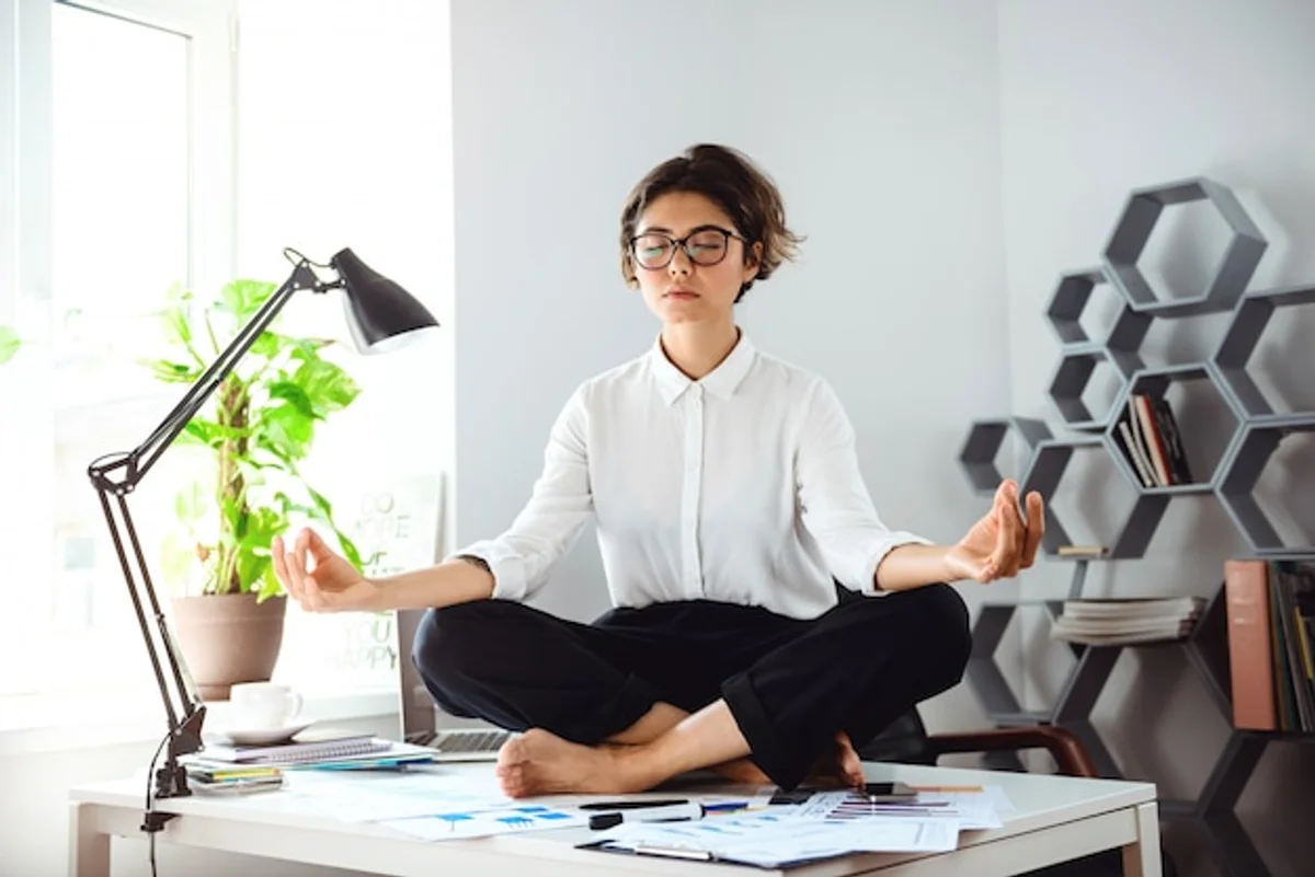 young professional meditating at work desk