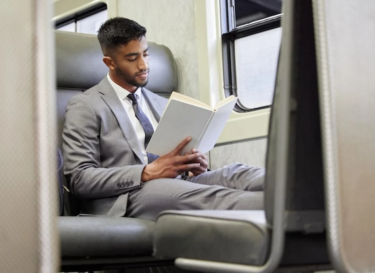 young professional reading book on train in morning