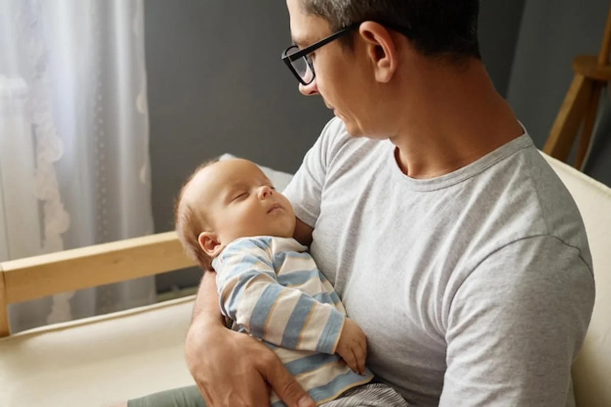 Tired young parents with baby at night, low light living room