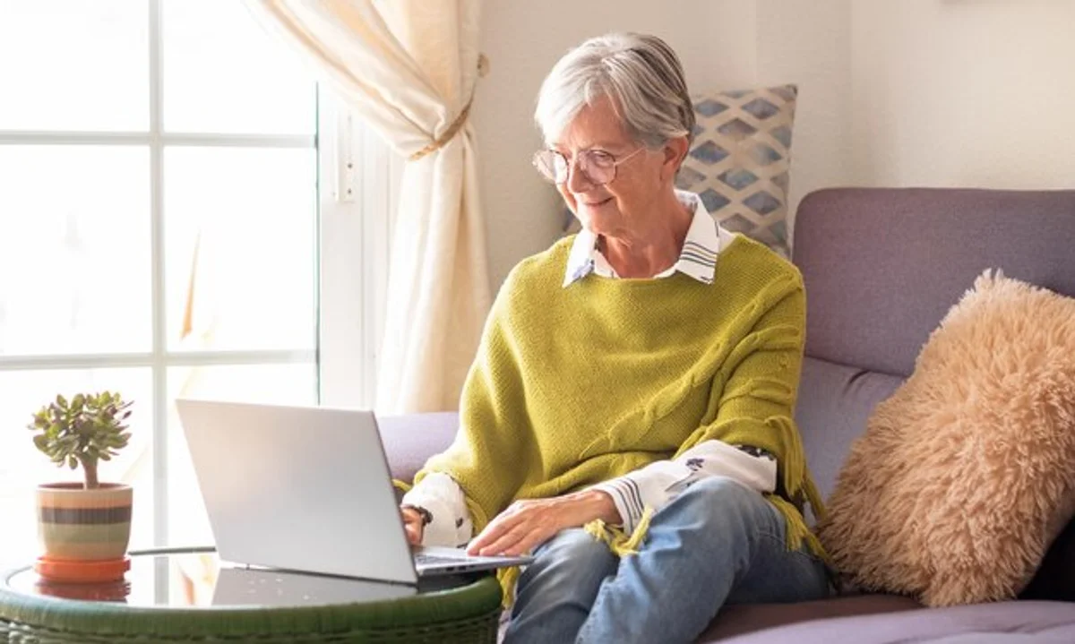 senior citizen using modern tablet at home, smiling, bright room