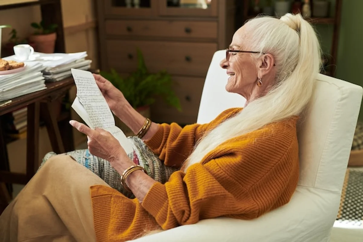 senior writing letter smiling cozy living room