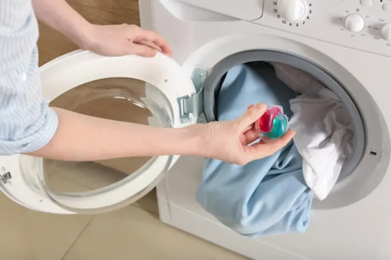 person putting detergent into washing machine