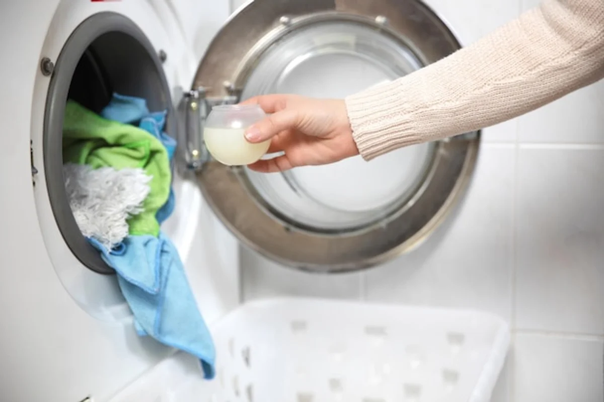 person measuring laundry detergent for washing machine