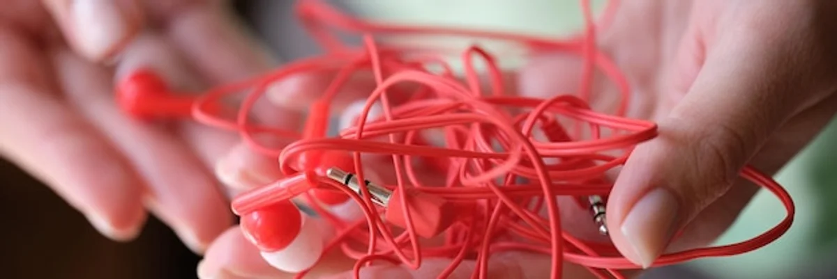 hands tying up tangled wired headphones