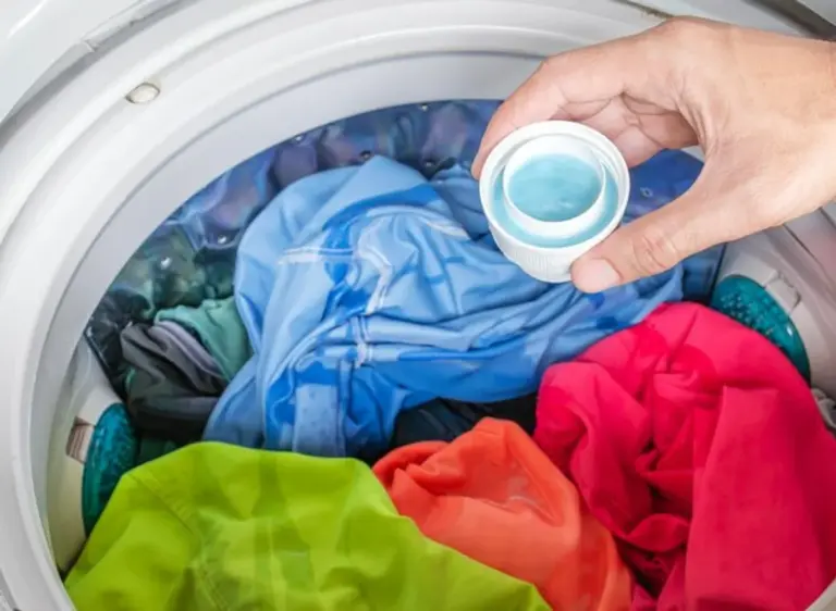 colorful clothes in washing machine with detergent, laundry care details