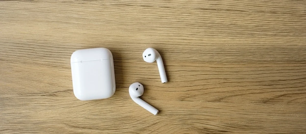 AirPods and budget wireless earbuds comparison on a modern desk