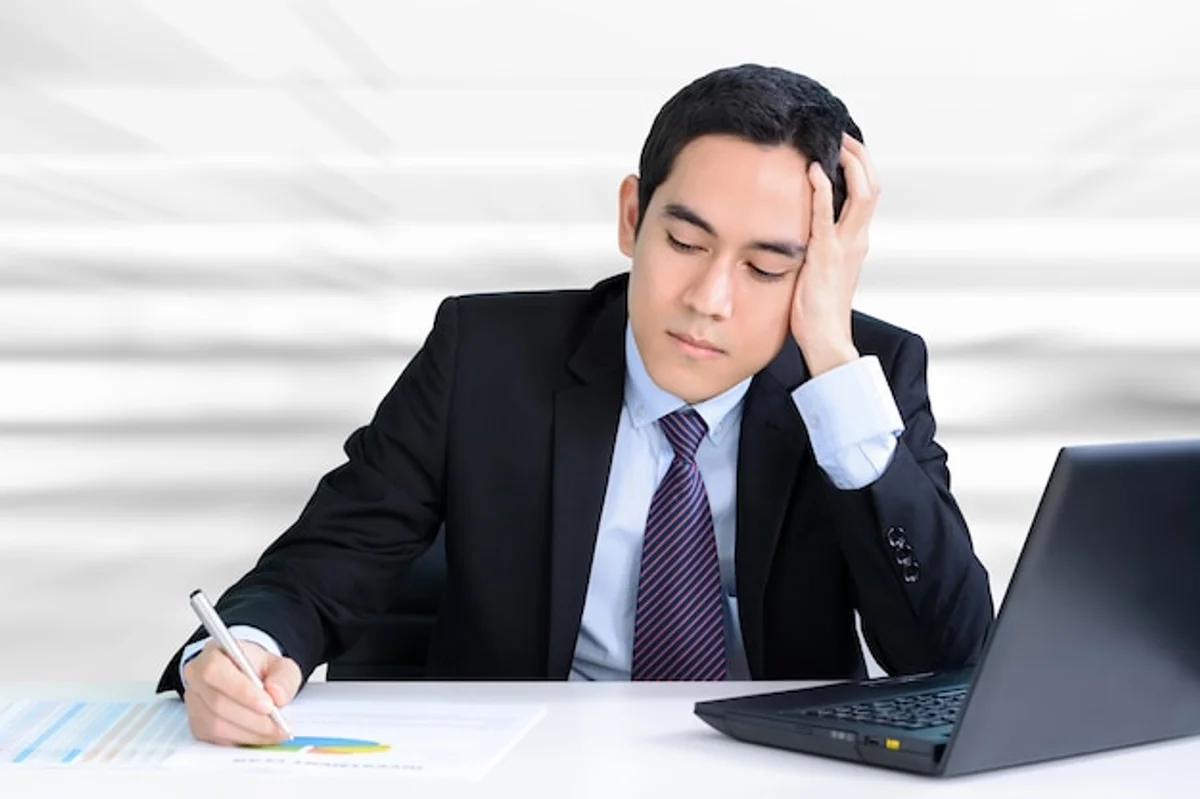 stressed business person with hand on forehead at desk